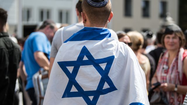  In eine israelische Fahne eingewickelt demonstriert ein Mann auf dem Marktplatz gegen Antisemitismus.